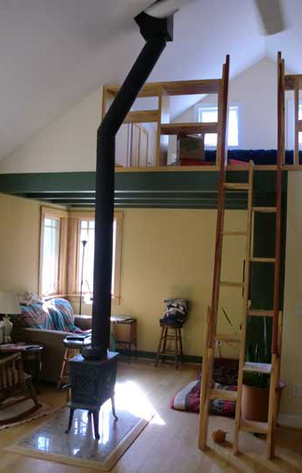 Freestanding wood stove next to a loft with a ladder