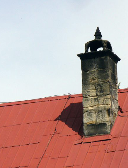 Older chimney with smoke damage on old metal roof