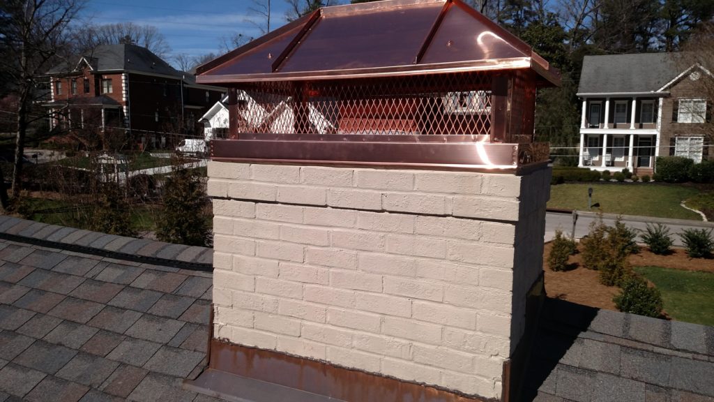 Nice copper chimney cap with homes in the background